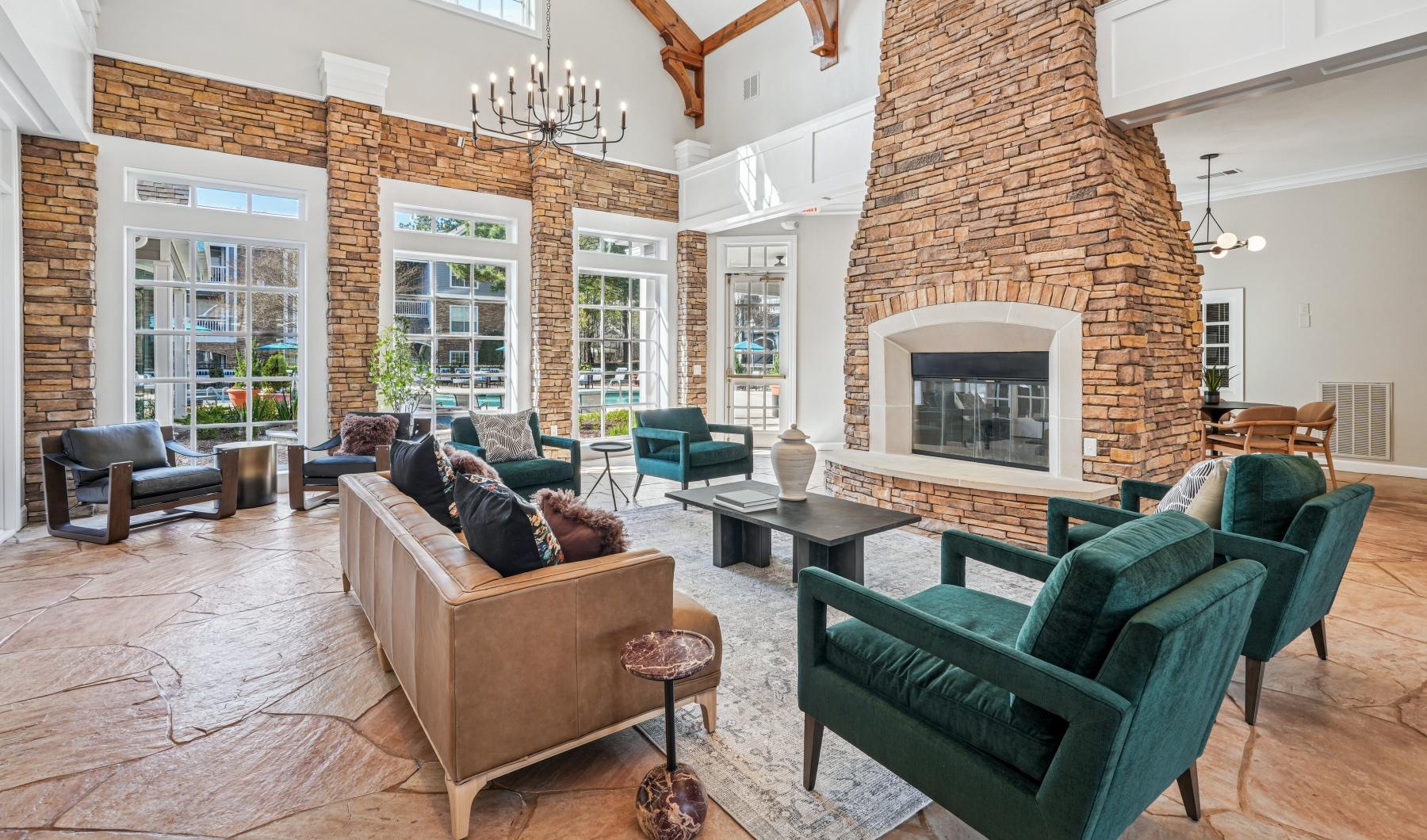 a clubroom with a couch, tables, chairs and a fireplace