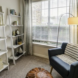 a room with a chair and a shelf with books